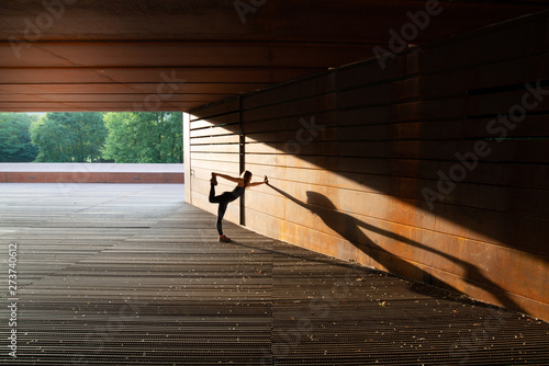 young woman stretching after running and leaning in a amazing geometrical building photo