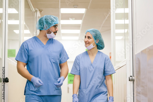 fellow surgeons man and woman chat while walking towards the operating theater photo