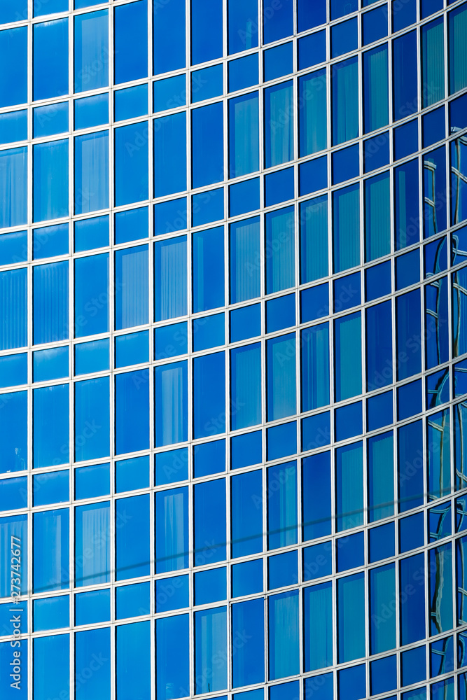 Glass facade of modern building reflecting blue sky