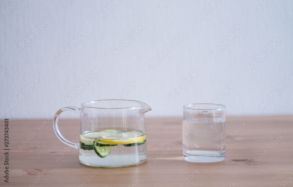 jug of lemonade and water sliced cucumbers and lemon on wooden table close up with blurred background jug of lemonade and water sliced cucumbers and lemon on wooden table close up with blurred background