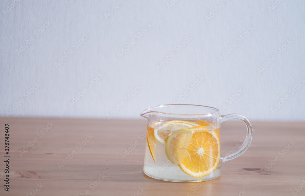 pitcher with lemonade and water sliced oranges and lemon on wooden table and coral and blue table background close up with blurred background pitcher with lemonade and water sliced oranges and lemon on wooden table and coral and blue table background close up with blurred background