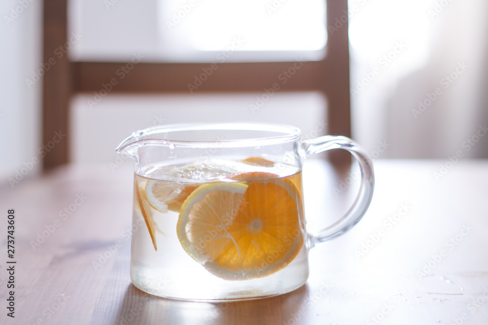 pitcher with lemonade and water sliced oranges and lemon on wooden table and coral and blue table background close up with blurred background pitcher with lemonade and water sliced oranges and lemon on wooden table and coral and blue table background close up with blurred background