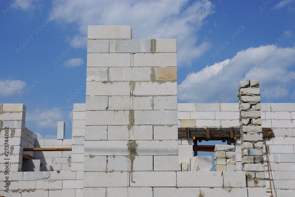 Obraz premium wall of an unfinished house of white bricks against the sky and clouds