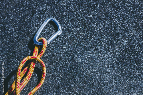 Carabiner on a texured roofing felt surface with many small grey stones photo