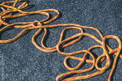 Bright tangled orange rope on a texured roofing felt surface with many small grey stones photo