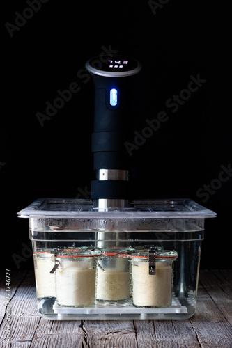 Cheesecake in glass tubs preparing in chief cooking sous-vide placed on wooden table on black background photo