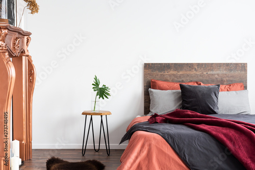 Canvas Print White interior with wooden bed, grey bedding, bedside table and coppery fireplac