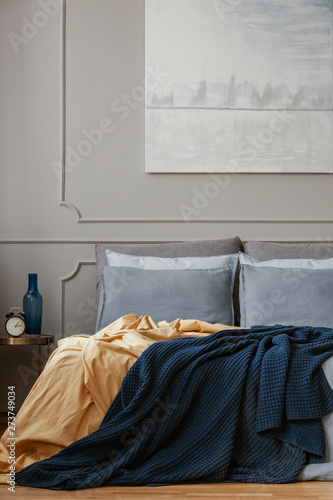 Dark blue blanket on king size bed in grey bedroom interior