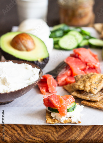Healthy breakfast ingredients: smoked salmon, liver pate, cucumber, tomato, avocado, mozzarella and cream cheese, multigrain crackers.  Breakfast served with coffee and milk. Healthy snacks.