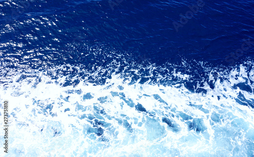 Rippled sea water in ink blue color tone and white sea foam, top view