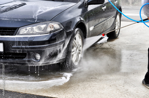 Cleaning Car Using High Pressure Water. Man washing his car under high pressure water in service © miccolino