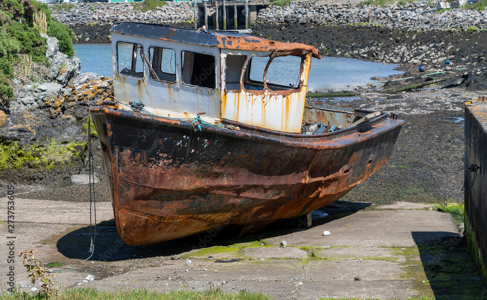 Rusting derelict boat left on a beach