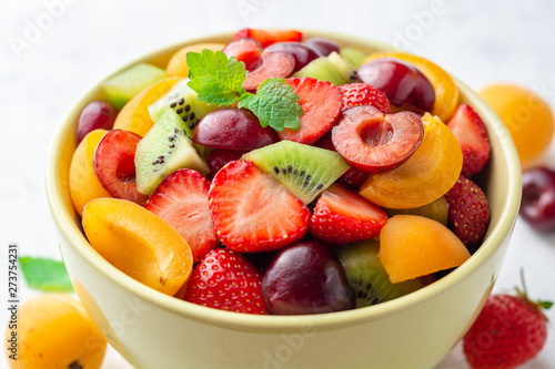 Healthy fresh fruit salad in bowl on gray concrete background. Selective focus.