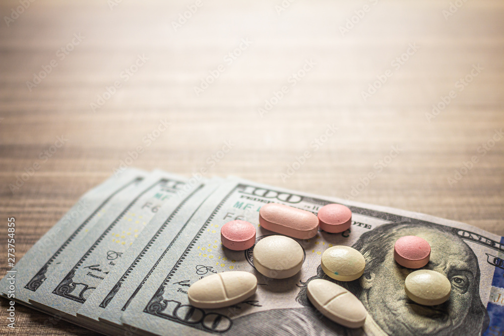 Concept of cost of medicines. Several Pills on a brown table with bills.