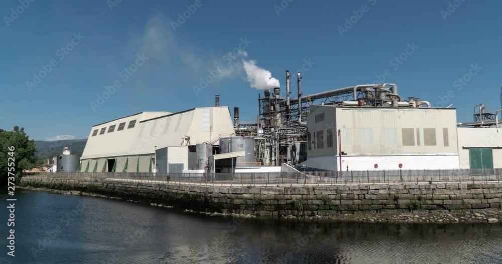 Timelapse of a Industrial Factory near a river with pipes emitting smoke Timelapse of a Industrial Factory near a river with pipes emitting smoke