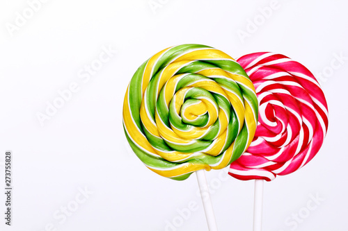 Red and green lollipops on white background. Lollipops with stripes. Round sweet candies on a white sticks. Copy space