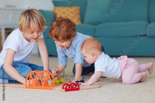 cute kids, siblings playing toys together on the carpet at home