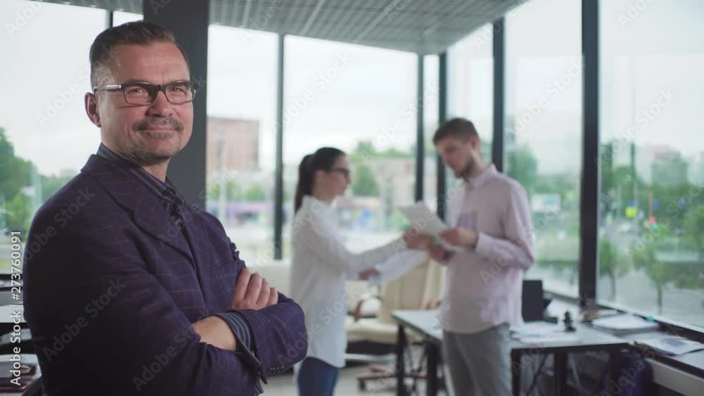 Successful businessman standing with arms crossed and smiling at camera in the office Successful businessman standing with arms crossed and smiling at camera in the office