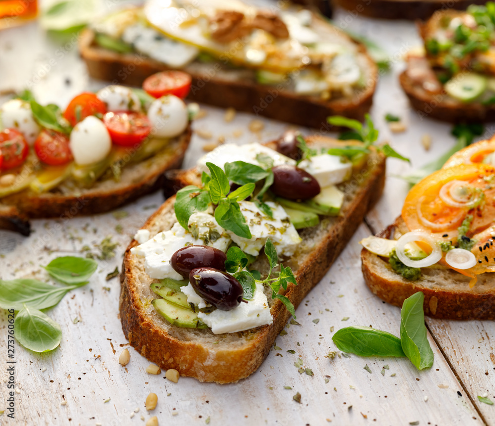 Open sandwich made of slices of sourdough bread with avocado, feta cheese, kalamata olives, olive oil and oregano on a wooden white table, close-up. Vegetarian food Open sandwich made of slices of sourdough bread with avocado, feta cheese, kalamata olives, olive oil and oregano on a wooden white table, close-up. Vegetarian food