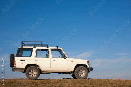 White jeep parked on a high hill off-road.