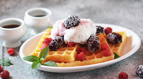Belgian waffles with ice cream, mint and frozen raspberries and blackberries. Tasty breakfast.