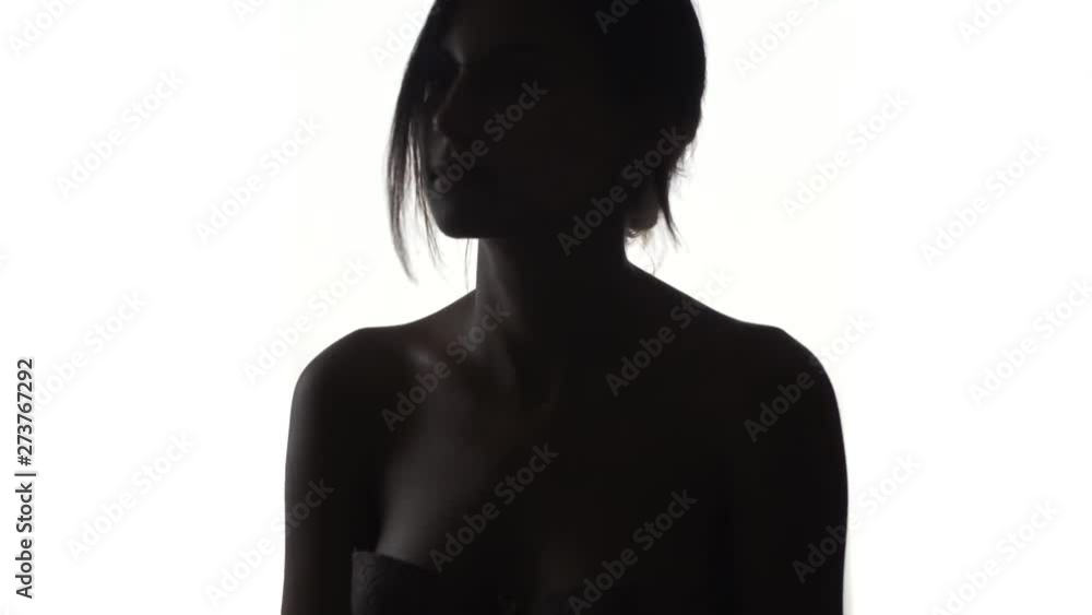 Silhouette of woman with wind in hair, turning her head from one side to another, shot in slow motion Silhouette of woman with wind in hair, turning her head from one side to another, shot in slow motion