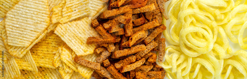 Assortment of Unhealthy Snacks: chips, onion rings, crackers top view, flat lay. Unhealthy eating concept. Assortment of Unhealthy Snacks: chips, onion rings, crackers top view, flat lay. Unhealthy eating concept.