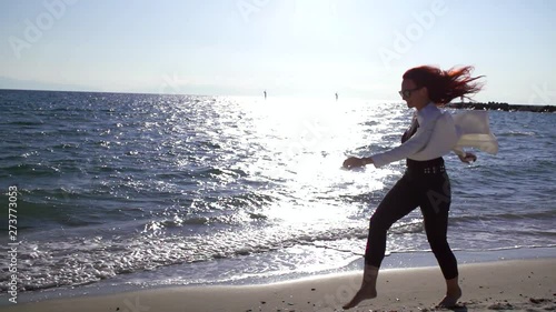 Outdoor shooting of a happy woman leaping on the beacho wearing summer sunglasses and light clothes. photo