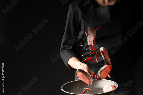 Chef fried fish with small red hot pepper on a griddle against a black background. horizontal photo. sea food. healthy food. oriental cuisine, baner photo