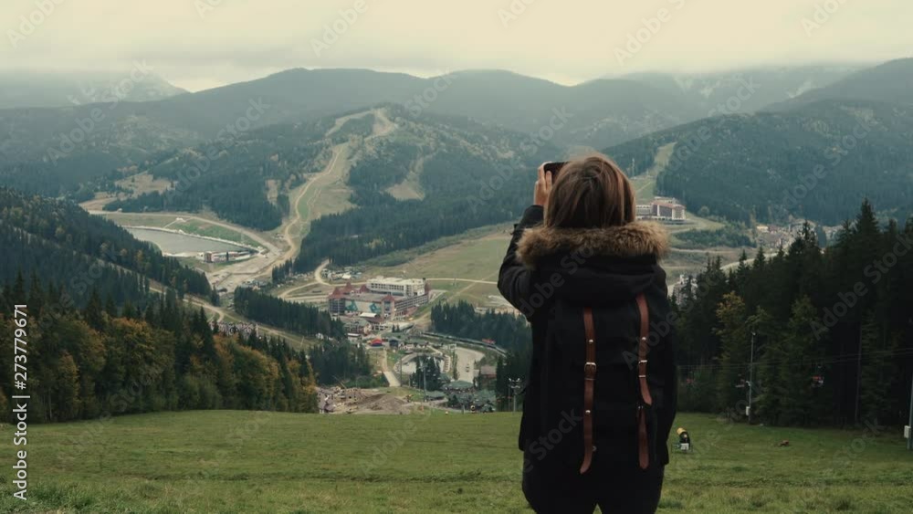 Young girl hiker is shooting video of beautiful misty mountain landscape on mobile phone camera. Lifestyle adventure. Back view, toning, 4k, Editorial video Young girl hiker is shooting video of beautiful misty mountain landscape on mobile phone camera. Lifestyle adventure. Back view, toning, 4k, Editorial video