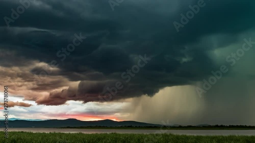 Dramatic thunderstorm with lightning over the lake during sunset, timelapse video. Beautiful fiery clouds with scary thunderclouds and an impending torrent of rain photo