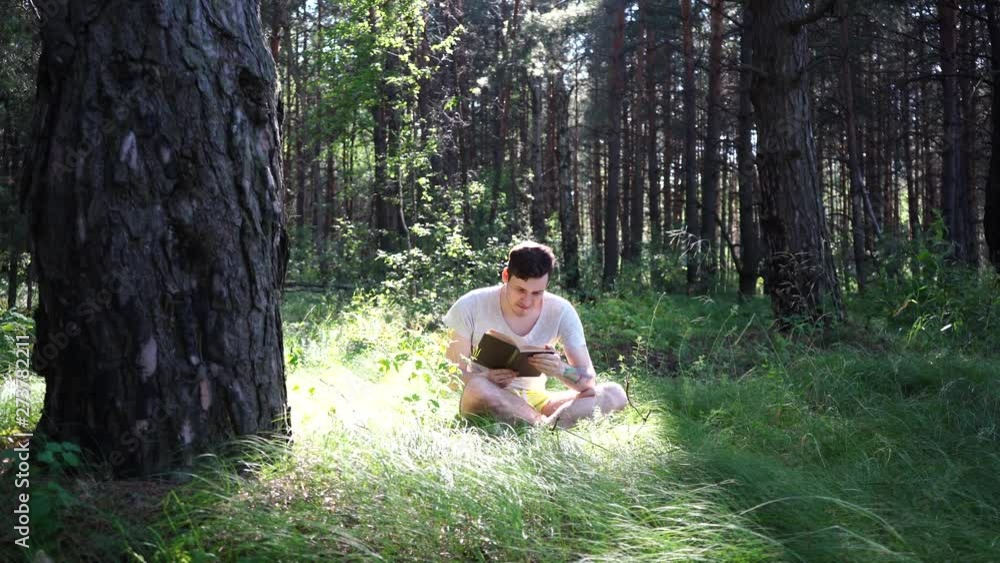 Man reading a book in a green summer forest. Man reading a book in a green summer forest.