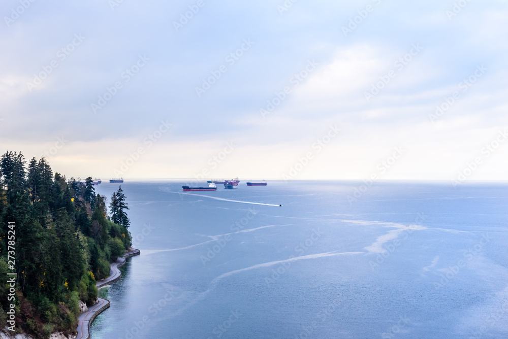 Cargo ships and boat in bay near shore in Vancouver, BC, Canada.