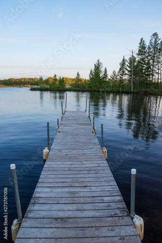 Low angle view of pier jutting out into the Chippewa Flowage in front of a wooded island in the Northwoods forest of Hayward, WI