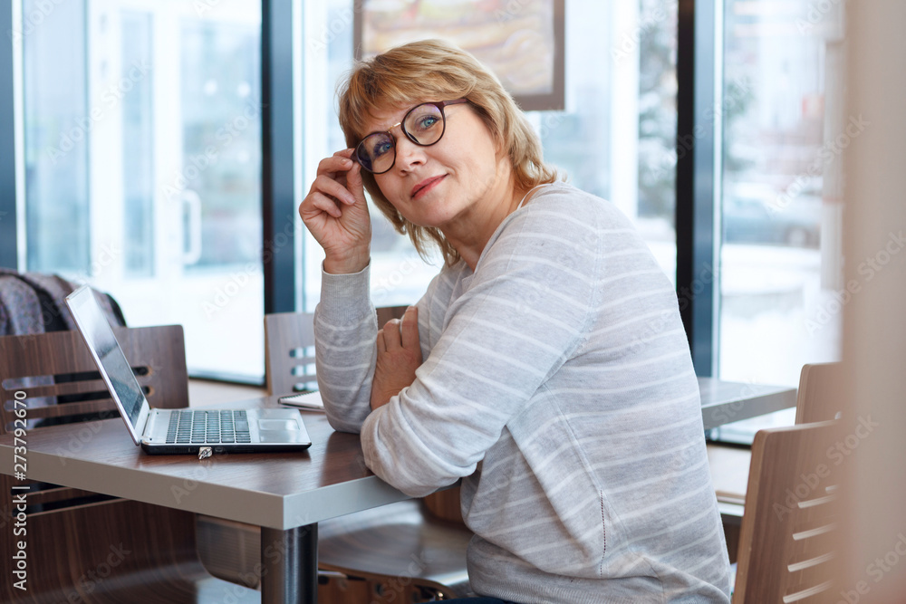middle-aged woman business in workplace in cafe, office, she's working on her laptop. middle-aged woman business in workplace in cafe, office, she's working on her laptop.