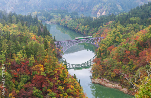 First bridge and Tadami river in beautiful autumn season with train crossing the bridge.