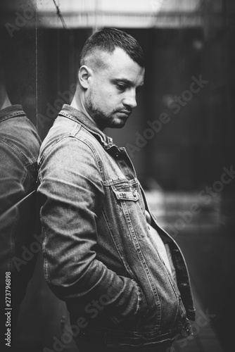 pensive guy stand near the wall black and white photo