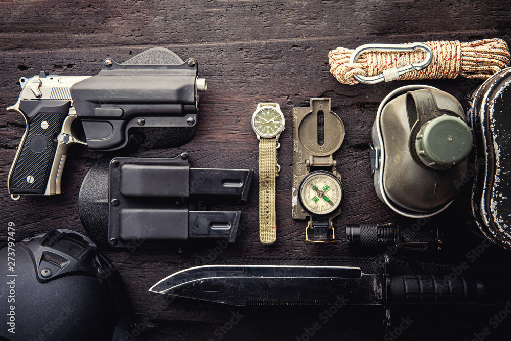 Military tactical equipment for the departure. Assortment of survival  hiking gear on wooden background. Top view - vintage film grain filter  effect styles Stock Photo