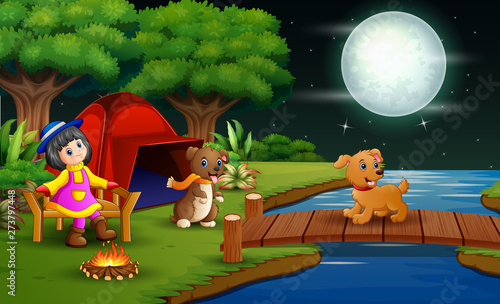 Little girl camping in the forest at night with her pet