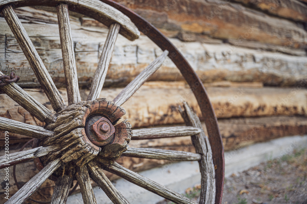 An old wooden wagon wheel with a rusty chain wrapped around it.