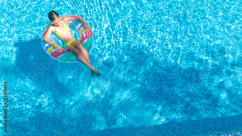 Acrive girl in swimming pool aerial top view from above, kid swims on inflatable ring donut , child has fun in blue water on family vacation resort © Iuliia Sokolovska