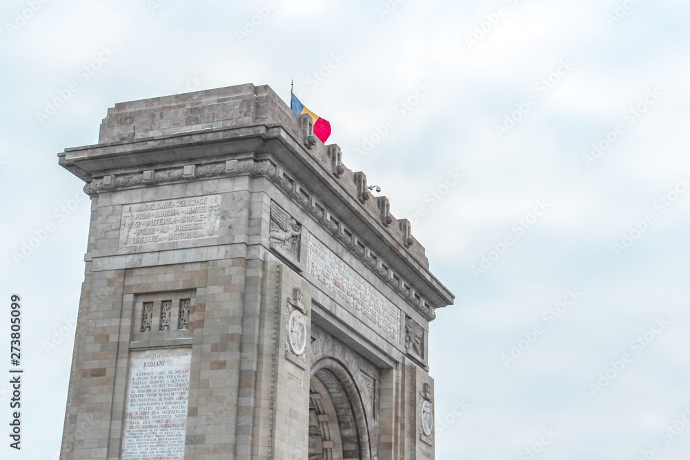 The image of Arcul de Triumf (Triumphal Arch) with flag in cloudy sky in winter season, Bucharest, Romania. It is located in the northern part of Bucharest, on the Kiseleff Road. The image of Arcul de Triumf (Triumphal Arch) with flag in cloudy sky in winter season, Bucharest, Romania. It is located in the northern part of Bucharest, on the Kiseleff Road.