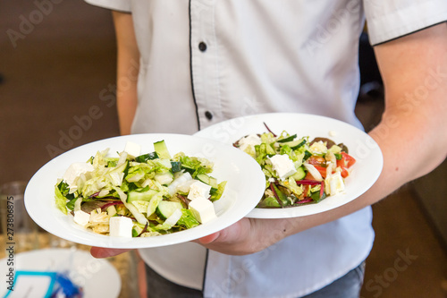 Fototapeta Naklejka Na Ścianę i Meble -  Waiter hold two plates of salad, work on event serviсе.