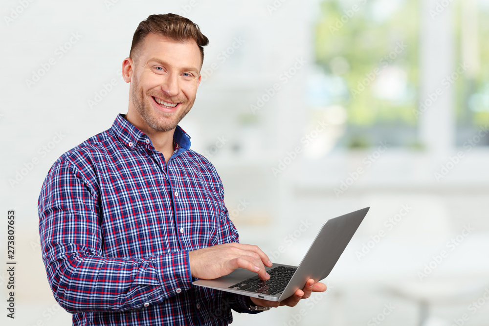 Young man standing, holding laptop computer, working. Young man standing, holding laptop computer, working.