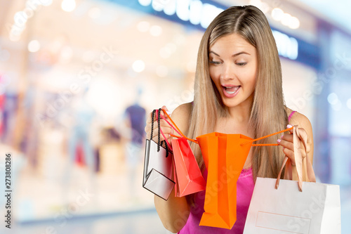 smiling young woman with shopping bags over mall background
