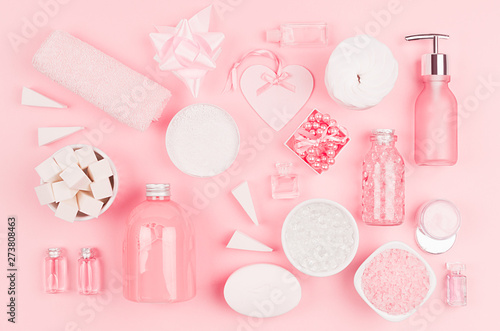 Cosmetic products for bathroom, health and hygiene in modern girlish style - decorative heart, soap, bath salt, essential oil, cream, towel, perfume, pearls, gift box on pink background.