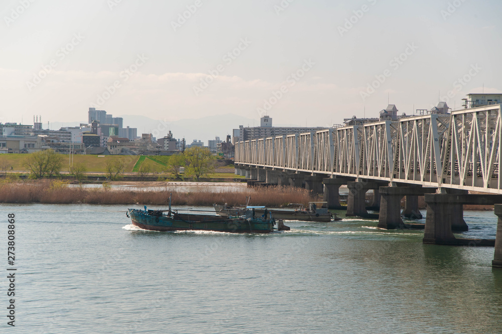 淀川の鉄橋の下を航行する船
