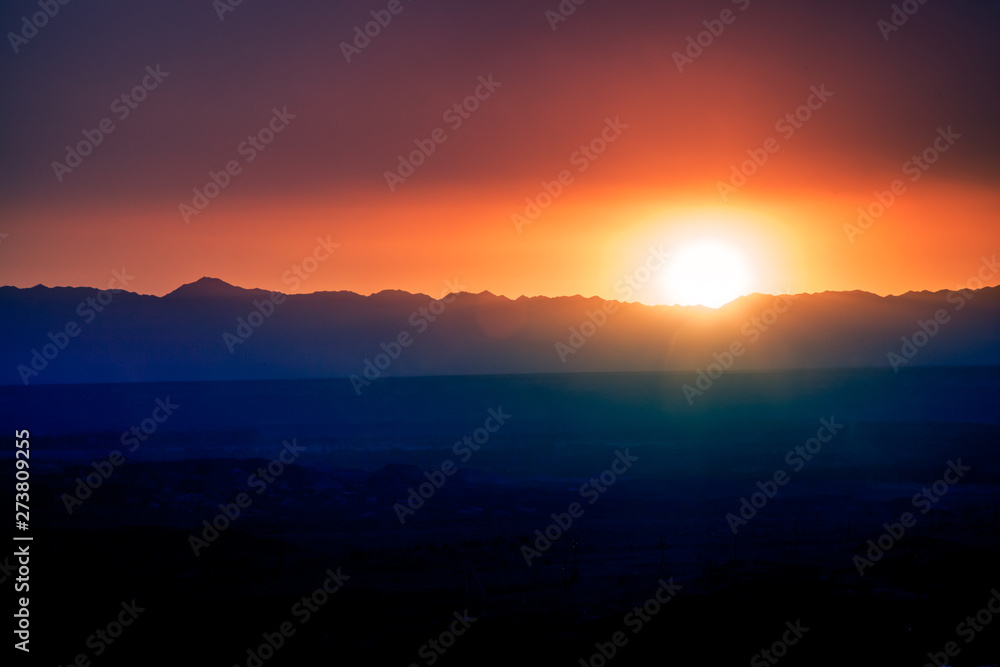A warm sunset over the highway in a purple-orange color with mountains on the horizon