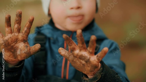 Close-up little playful boy showing dirty in ground hands naughty child enjoying happy childhood