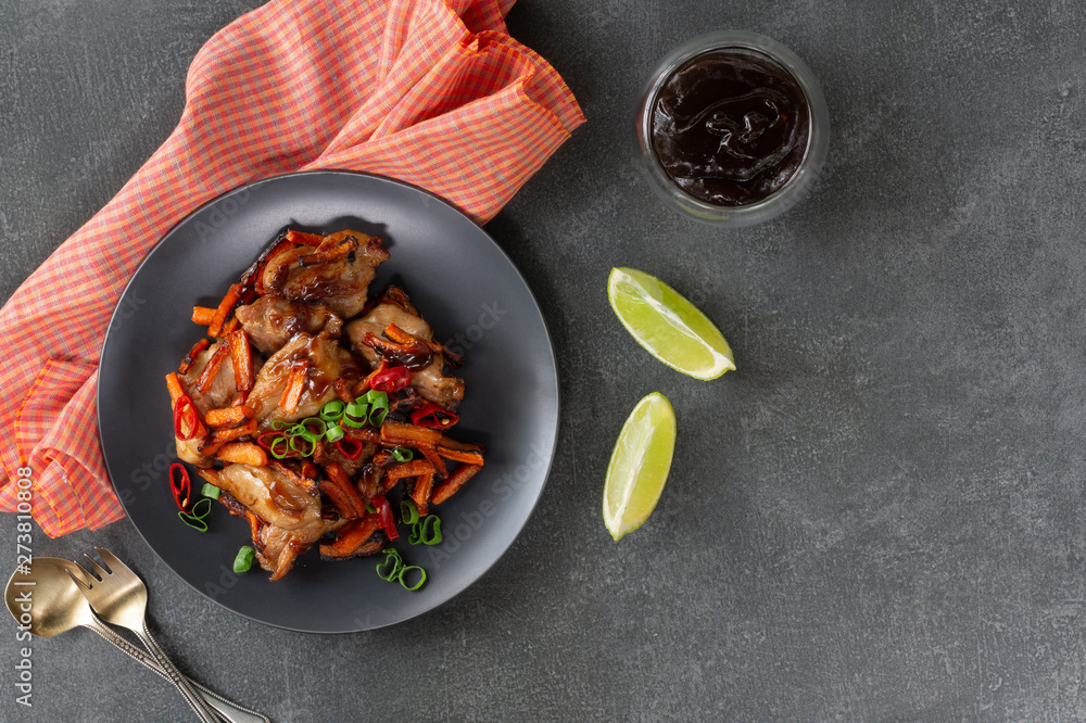 Teriyaki chicken with carrots, green onions and lime on a dark background